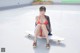 A woman in a bikini sitting on a skateboard.