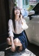 A woman sitting on the ground next to a white car.