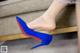 A close up of a woman's legs wearing blue and red shoes.