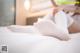 A woman laying on a bed with her feet up in white socks.