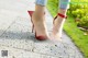 A woman wearing a pair of red high heels on a sidewalk.