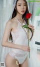 A woman in a white lingerie holding a red rose.