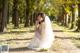 A woman in a wedding dress sitting on a dirt road.