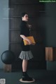 A woman standing in front of a book shelf holding a yellow purse.