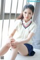 A young woman sitting on the floor in a school uniform.