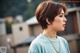 A woman with a short brown hair wearing a blue shirt.