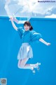 A woman jumping in the air holding an umbrella.