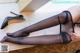 A woman in black stockings and high heels laying on a table.